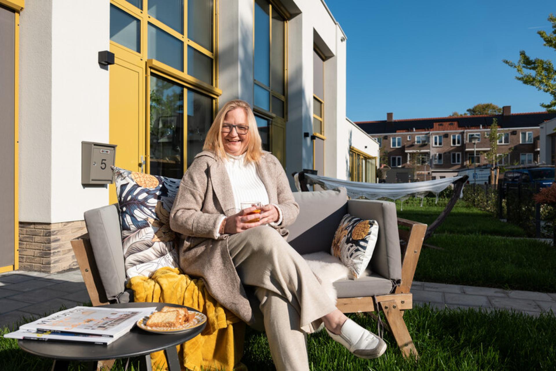 Vrouw op bankje voor huis