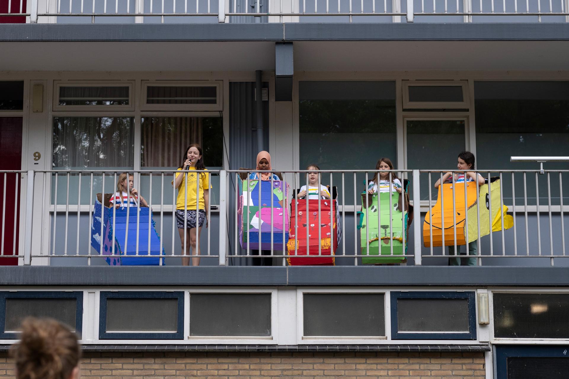 Kinderen maken theater op de galerij van Wagenaarflat