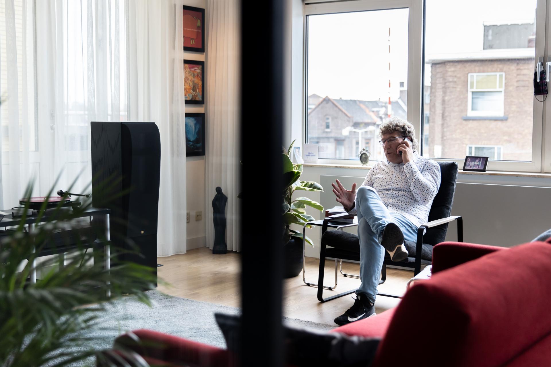 Ruud Geelhoed in zijn woonkamer aan de telefoon