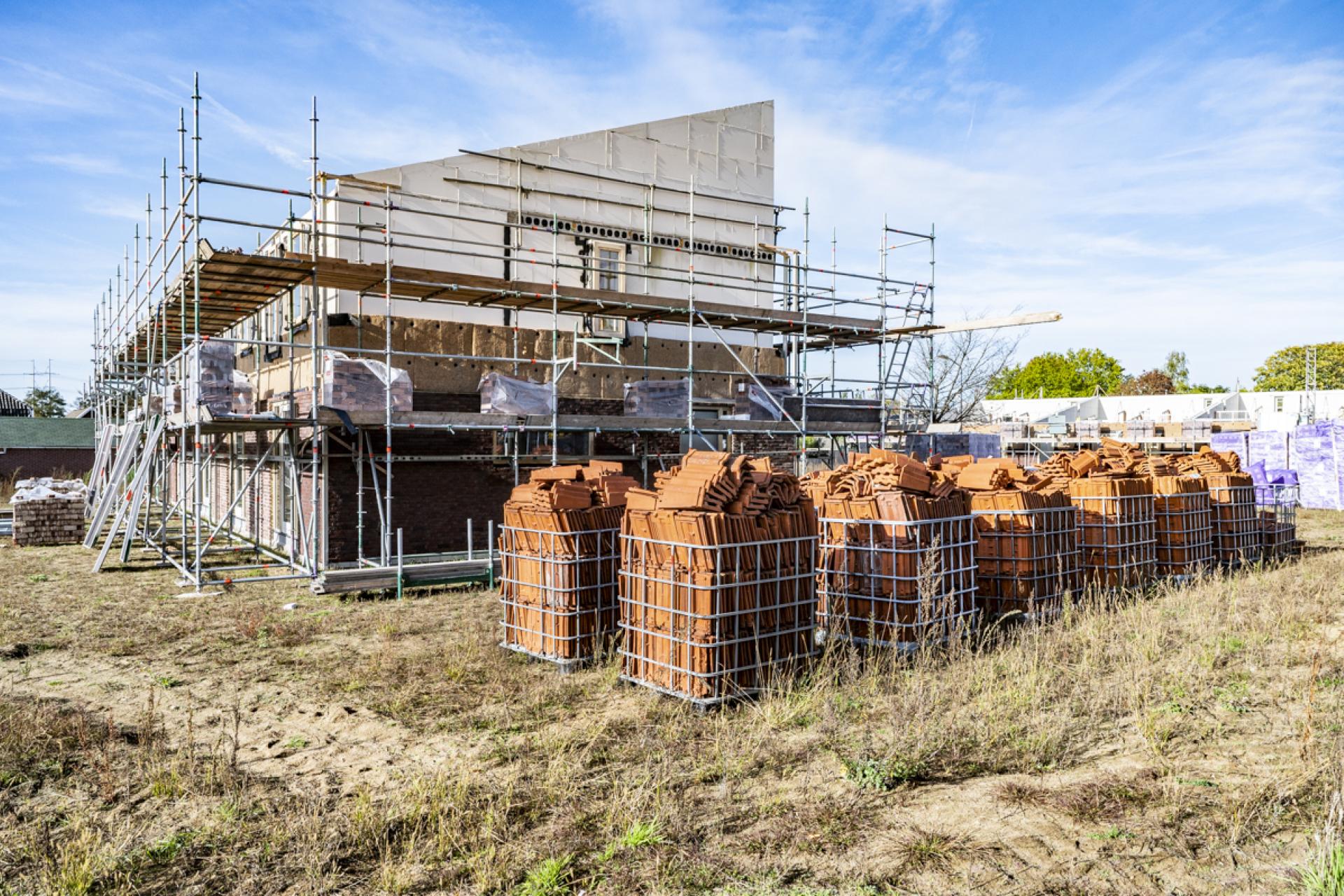 Huizen in aanbouw met voorraad herbruikbare dakpannen ervoor